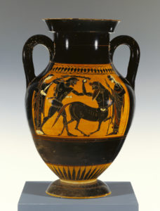 Large Greek storage jar, there is a motif on the central band of the jar showing a Greek man fighting a centaur, with two individuals flanking them. The background on the pot is a warm orange, and the characters are in black. Most of the pot including the handles and base are also black. 