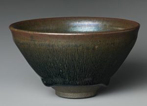 Bowl made from stoneware, colours include green, brown, blue and yellow that have melted and melded together. The bowl is very well shaped and smooth. 