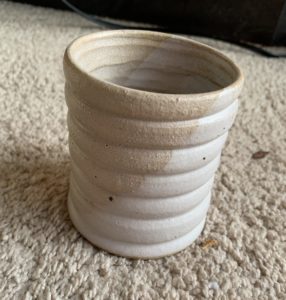 light brown and white beehive style cup on brown carpet