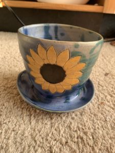 flower pot with sunflower, splattered with blue and teal on carpet